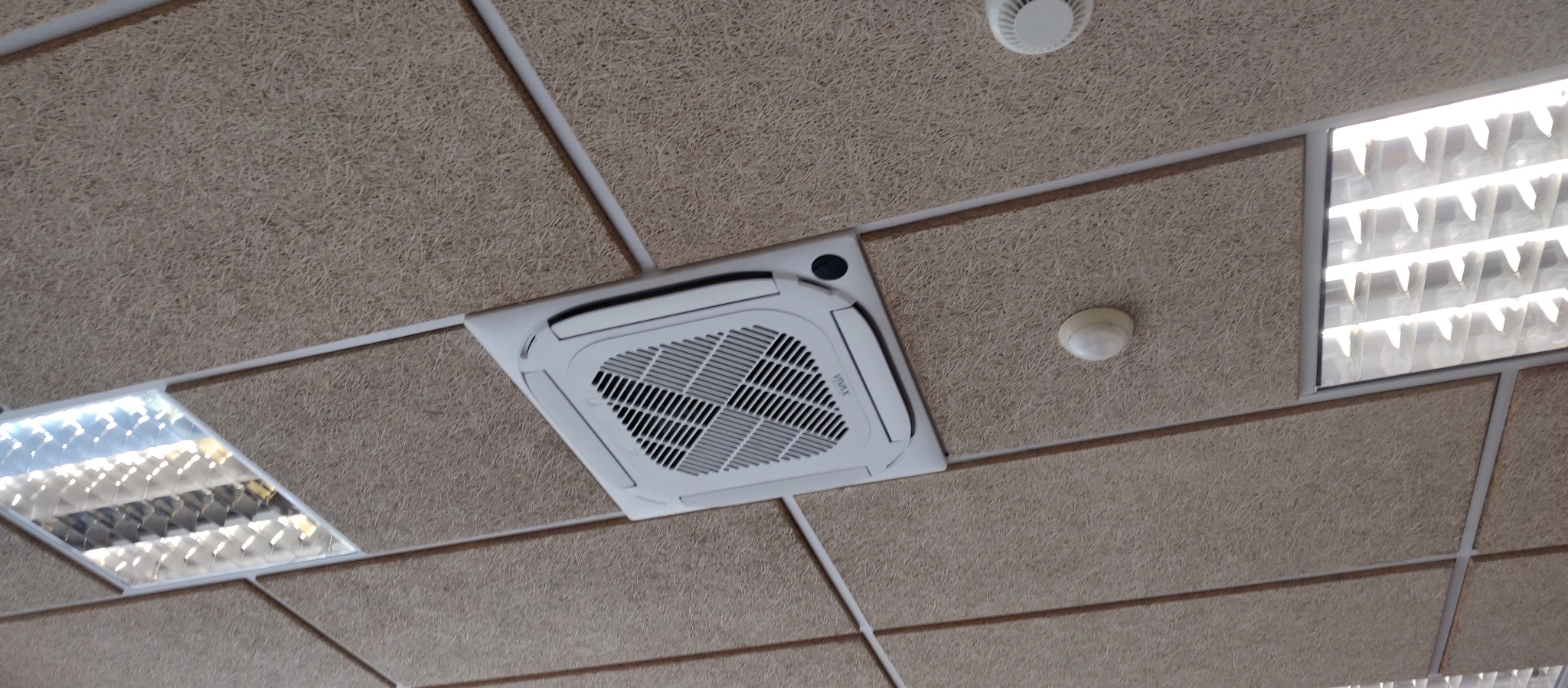 Sufit podwieszany z wbudowaną klimatyzacją kasetonową Vivax, oświetleniem LED i czujnikiem dymu. Widok z dołu.