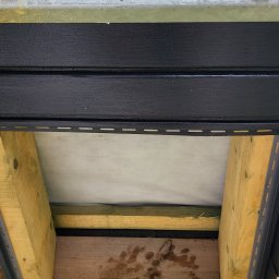 Morozov BUD - Fragment konstrukcji dachu z widoczną membraną, drewnianymi belkami i czarną podbitką. Widoczne elementy montażowe i izolacja. Ujęcie od dołu.