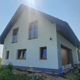 Morozov BUD - Jasny, dwukondygnacyjny dom z garażem i szklanymi balustradami. Widoczne bloczki budowlane i częściowo zaparkowany bus.