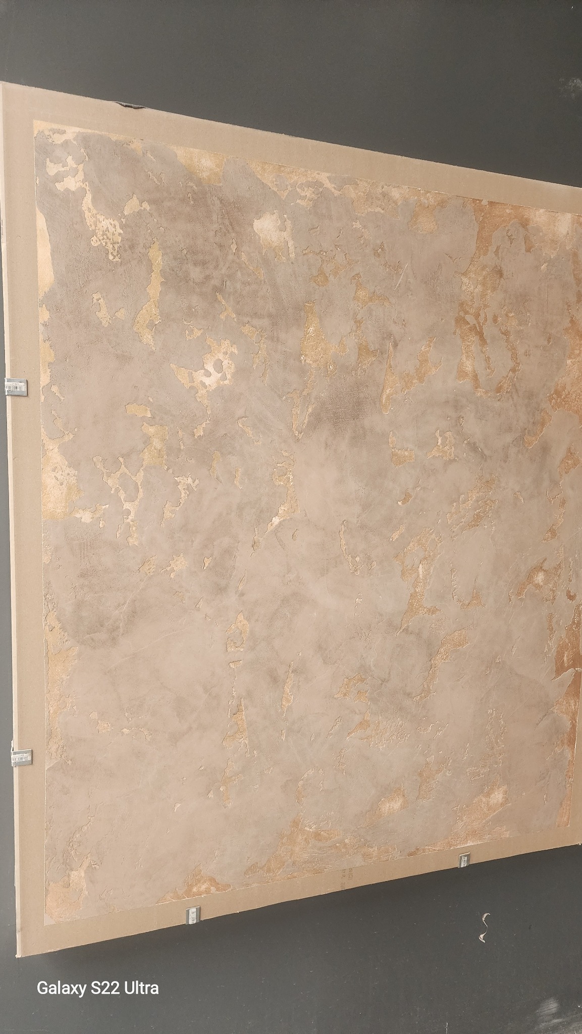 Dekoracyjna ściana z efektem patyny w odcieniach beżu i złota, wykonana techniką strukturalną. Widoczne nierówności i przetarcia tworzą unikalny, artystyczny wygląd.