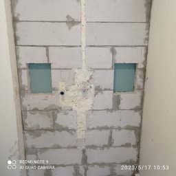 ZAG-BUD USŁUGI WYKOŃCZENIOWE i BUDOWLANE - Ściana z białych bloczków z wyciętymi otworami na instalacje, wypełniona pianką montażową w pionowym kanale, przygotowana pod dalsze prace wykończeniowe.