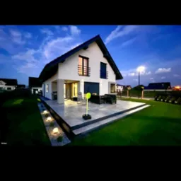 Nowoczesny dom jednorodzinny z tarasem i oświetleniem ogrodowym, widok wieczorny.