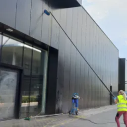 Mycie elewacji budynku salonu samochodowego w Kielcach za pomocą długiej lancy i specjalistycznego sprzętu czyszczącego.