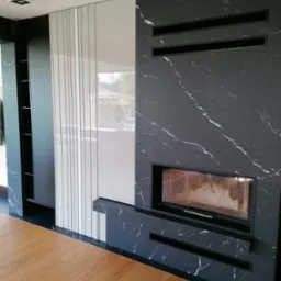 Zabudowa ściany w salonie, połączona z kominkiem.