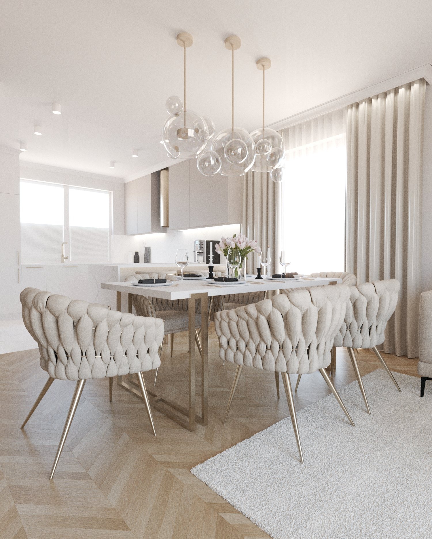 Jasne wnętrze jadalni z otwartą kuchnią, krzesła z welurowym obiciem w kolorze écru, stół z białym blatem i złotymi nogami, szklany żyrandol w kształcie kuli, parkiet w jodełkę, biały dywan.