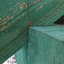 Fragment konstrukcji dachu z impregnowanego drewna, widoczna linia wyznaczająca cięcie, w tle śnieg.