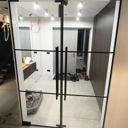 Perfekt Glass - Nowoczesne, dwuskrzydłowe drzwi szklane z czarnymi szprosami, widok na przedpokój z szafą i lustrem. W tle widoczne buty i legowisko dla psa.