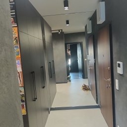 Perfekt Glass - Wnętrze korytarza z lustrem, które optycznie powiększa przestrzeń. Widoczne szafy w zabudowie, drzwi wejściowe i oświetlenie sufitowe.