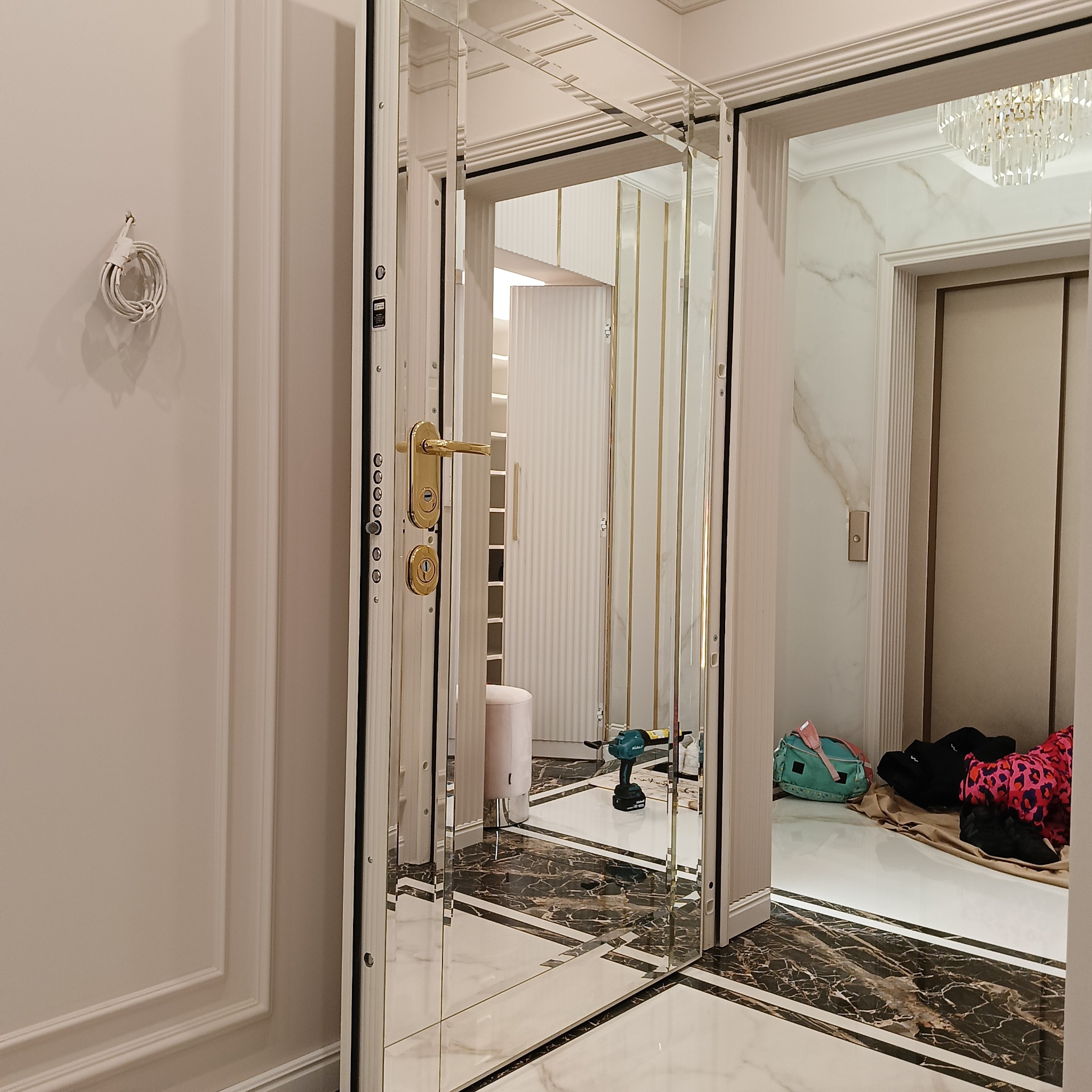 Szklane drzwi z złotymi akcentami, widok na wnętrze garderoby z narzędziami. Luksusowe wykończenie, marmurowa podłoga. Detal montażu.