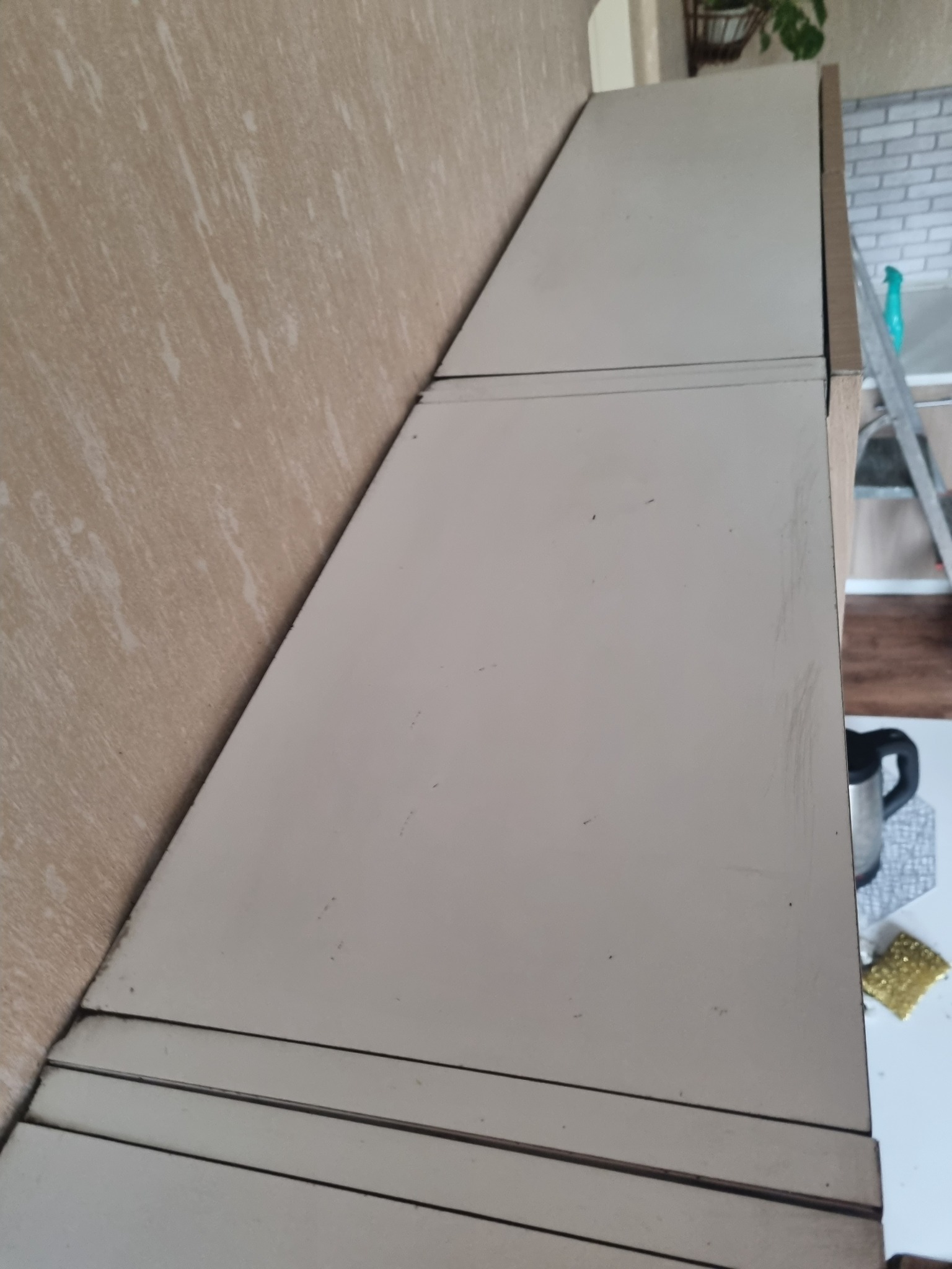 Fragment szafki z widocznymi zabrudzeniami i śladami użytkowania, obok drabina i akcesoria do sprzątania.