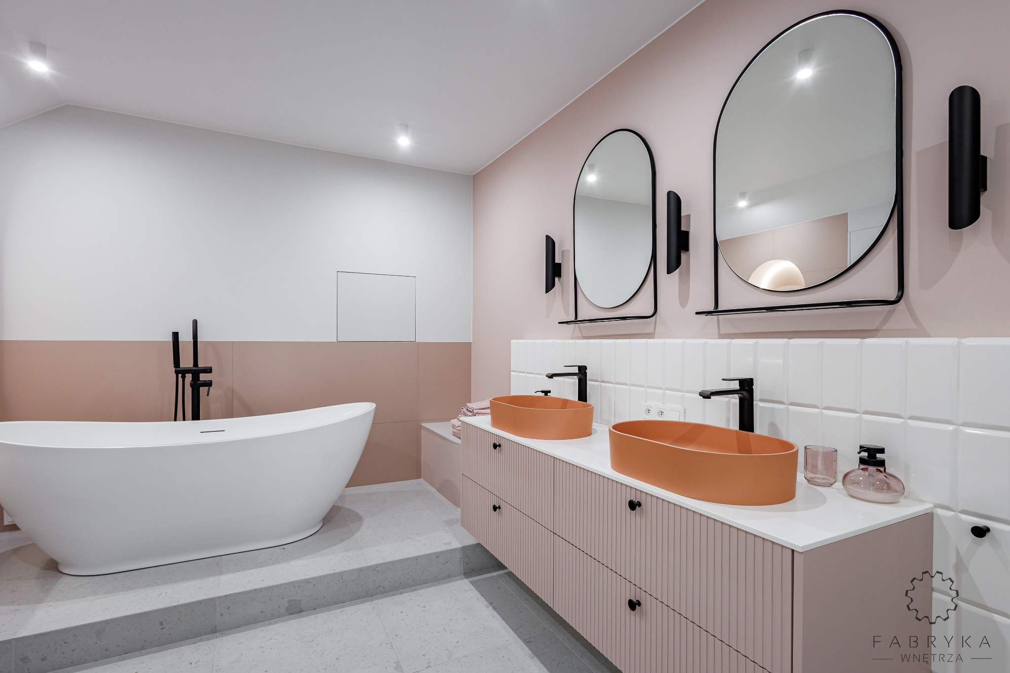 Nowoczesna łazienka w pastelowych odcieniach z wolnostojącą wanną, podwójną umywalką w kolorze terakoty i białymi płytkami typu metro na ścianie.