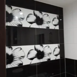 Czarno-biała glazura z motywem kwiatowym w wykończonej łazience w Koszalinie, widoczna armatura prysznicowa.