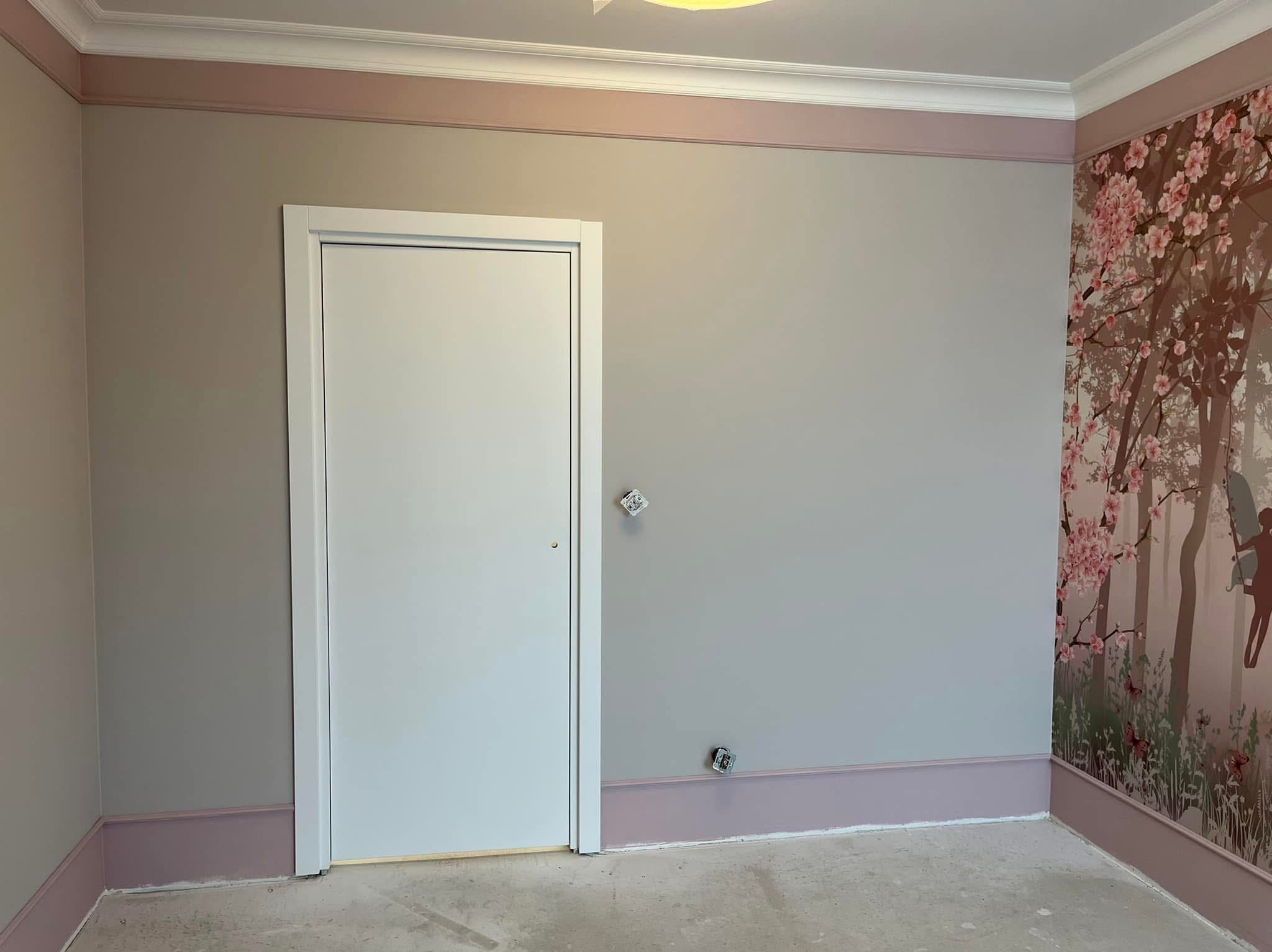 Pokój po remoncie: szare ściany z różowymi akcentami, białe drzwi i dekoracyjna tapeta w kwiaty wiśni. Widoczne gniazdka elektryczne.