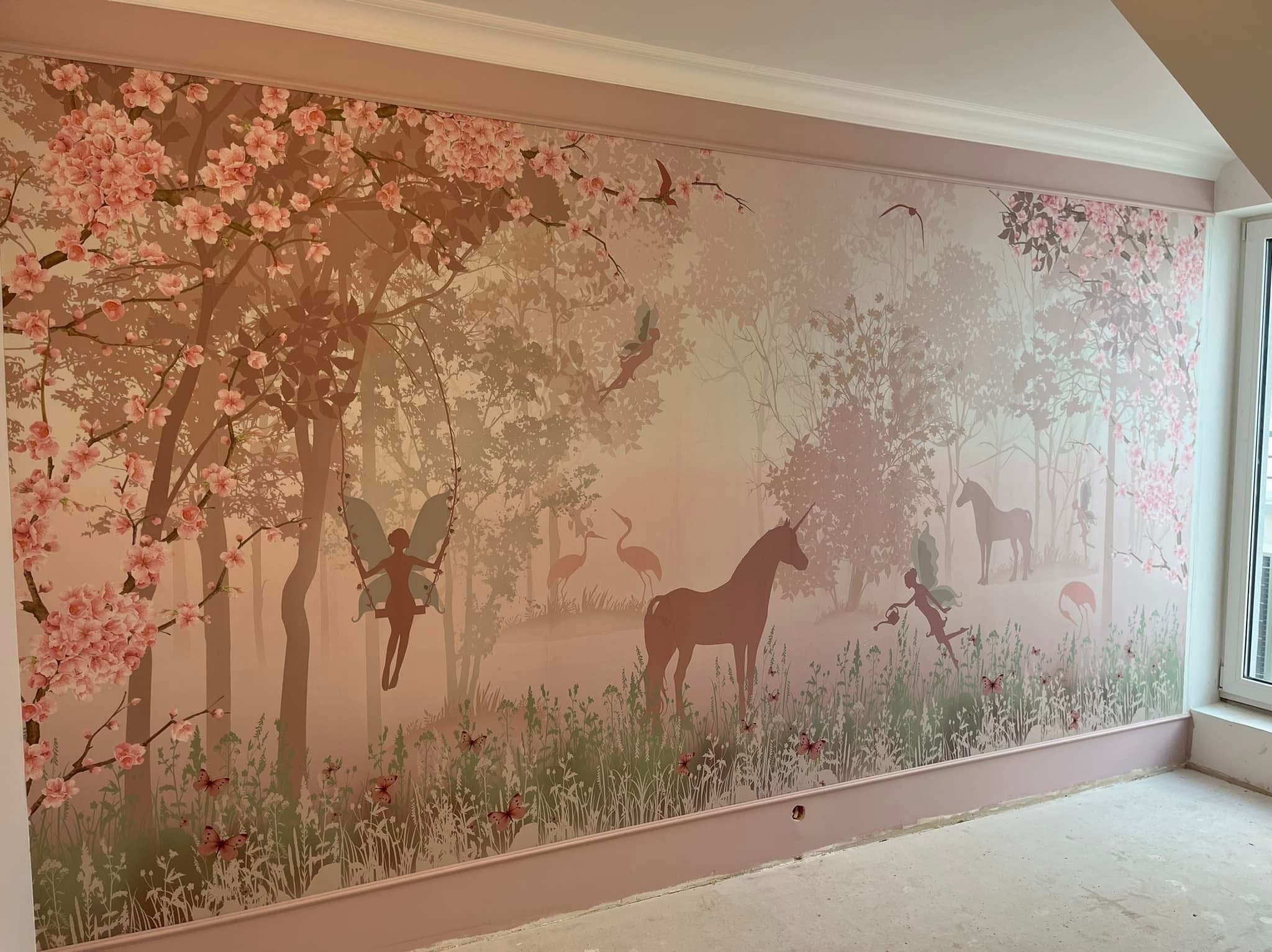 Pokój dziecięcy z bajkową tapetą: jednorożce, wróżki i kwitnące drzewa na ścianie z listwą przypodłogową w odcieniach różu. Wykończenie wnętrza.