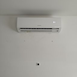 El-Rem Sp. z o. o. - Biała klimatyzacja Manta z wyświetlaczem 31 stopni Celsjusza zamontowana na białej ścianie. Widoczne ślady po poprzednim montażu.