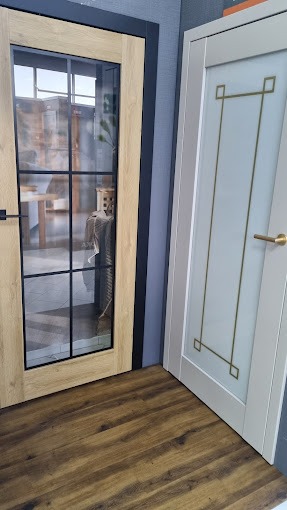 Dwa różne modele drzwi wewnętrznych: dębowe z czarnymi szprosami i przeszklonymi szybami oraz białe z matową szybą i geometrycznym wzorem w kolorze złotym.