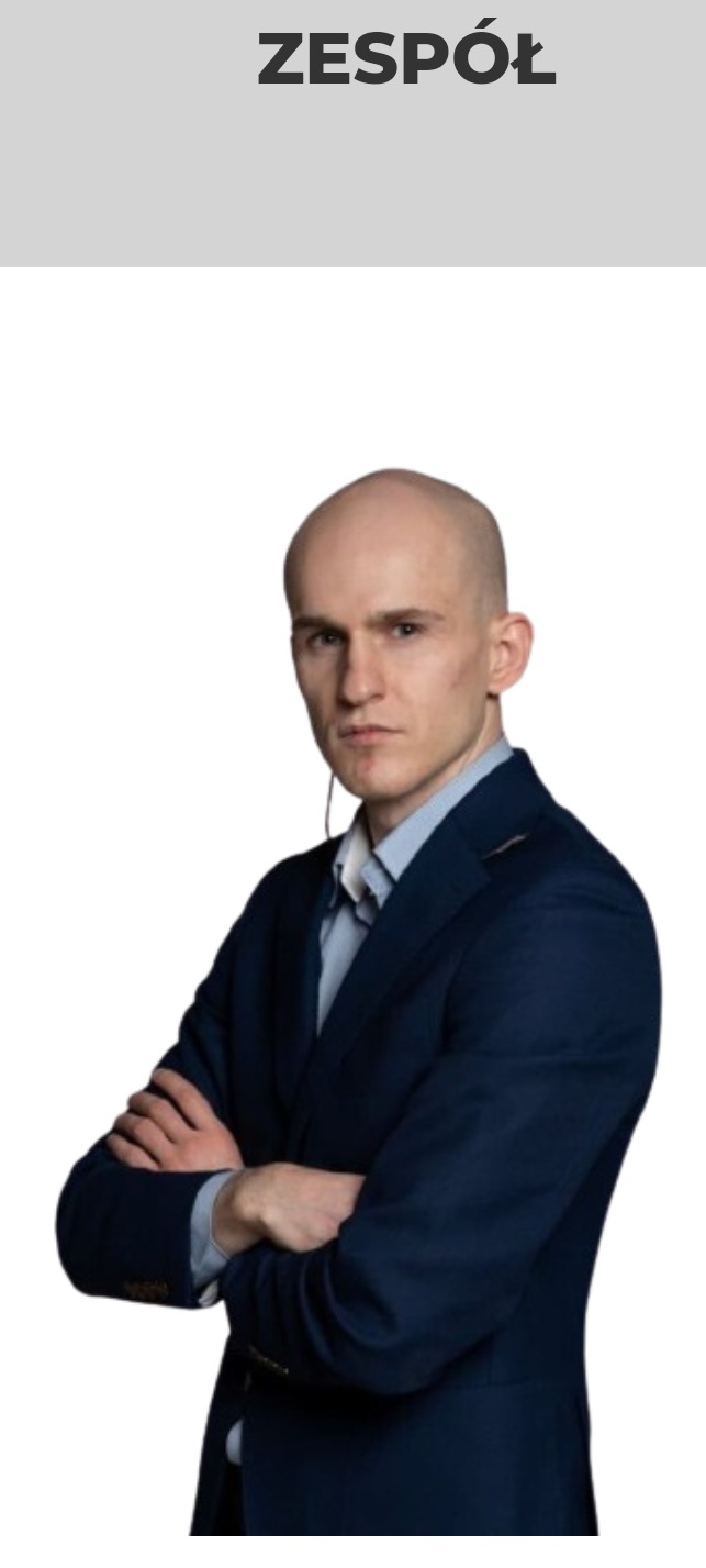 Portret mężczyzny w ciemnym garniturze i jasnej koszuli, z rękami skrzyżowanymi na piersiach, na białym tle, z napisem 'ZESPÓŁ' u góry.