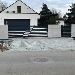 KAM SMART SP. Z O.O. - Nowoczesna, pozioma brama wjazdowa z geometrycznym wzorem, osadzona w jasnych, betonowych słupkach. Widok z ulicy na posesję z minimalistycznym domem.