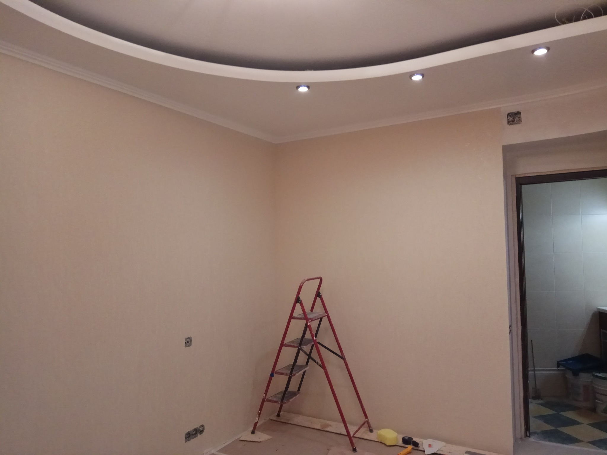 Pokój w trakcie remontu: ściany w kolorze ecru, czerwona drabina, sufit z podwieszaną konstrukcją i punktowym oświetleniem LED.