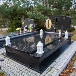 Granity Gdańsk - Dwa czarne, polerowane pomniki na cmentarzu, ozdobione kwiatami i lampionami, z refleksami nieba i drzew na powierzchni kamienia.