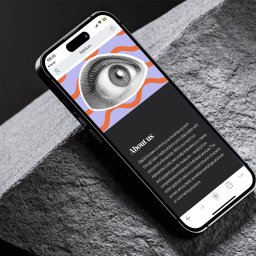 Recreate Sp. z o.o. - Ekran smartfona prezentuje stronę internetową 'bajola.eu' z sekcją 'About us' i graficznym motywem oka, na tle szarej, teksturowanej powierzchni.