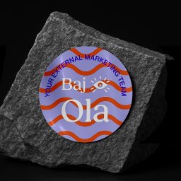 Recreate Sp. z o.o. - Okrągła naklejka z napisem 'Baj Ola, Your External Marketing Team' na szarym kamieniu na czarnym tle.  Fioletowo-pomarańczowa kolorystyka, nowoczesny branding.