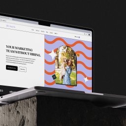 Recreate Sp. z o.o. - Laptop prezentuje stronę internetową Bajola.eu z hasłem 'Your marketing team without hiring' i grafiką kobiety z psem. Minimalistyczny design, nowoczesny interfejs.