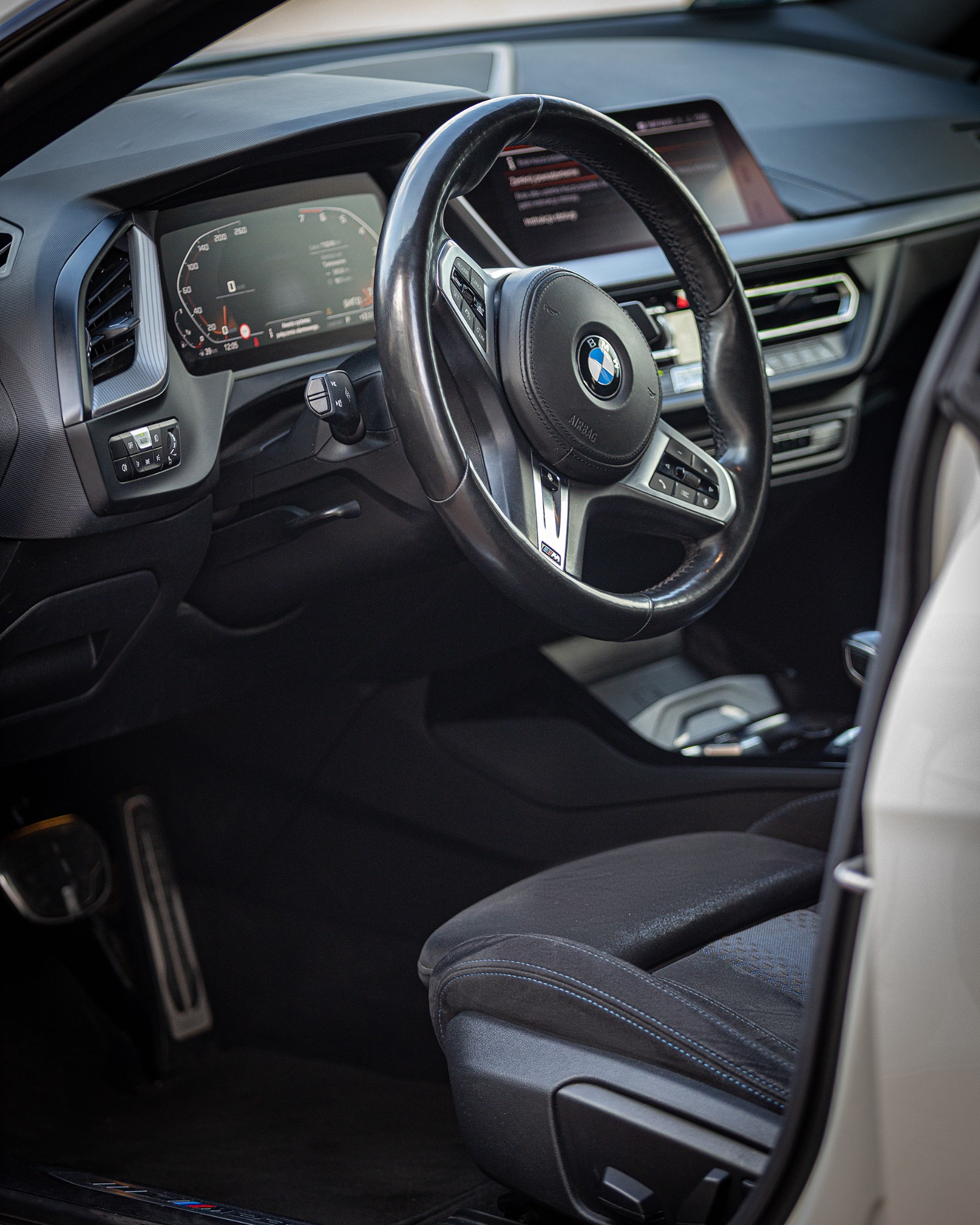 Wnętrze BMW Z4: czarna skórzana kierownica z logo, cyfrowy kokpit, sportowe fotele z niebieskimi przeszyciami, widok z otwartych drzwi.