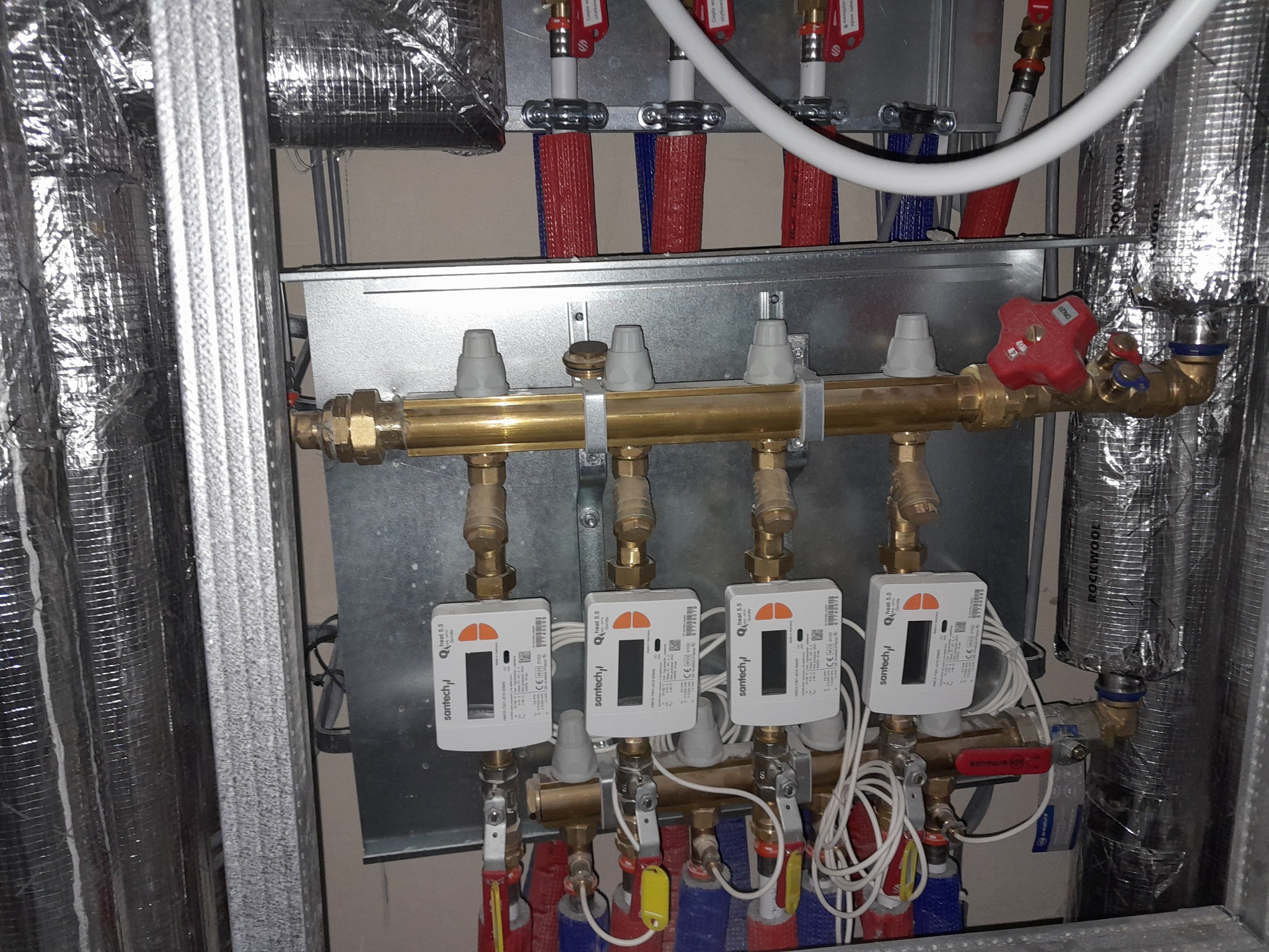 Rozdzielacz centralnego ogrzewania z licznikami ciepła SanTech Q heat 5.5 i izolowanymi rurami w folii aluminiowej