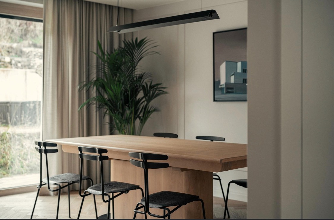 Jasne, minimalistyczne wnętrze jadalni w Kaliszu z dużym drewnianym stołem, czarnymi krzesłami i nowoczesną lampą wiszącą.