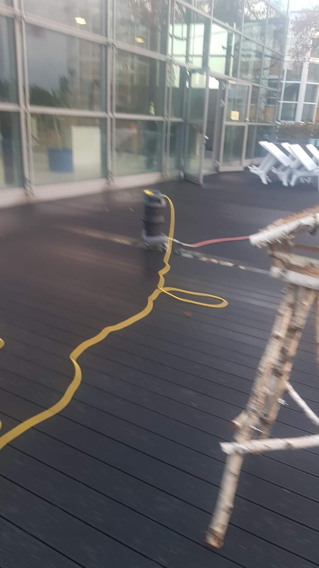 Sprzęt do czyszczenia elewacji budynku z licznymi oknami, w tle białe leżaki