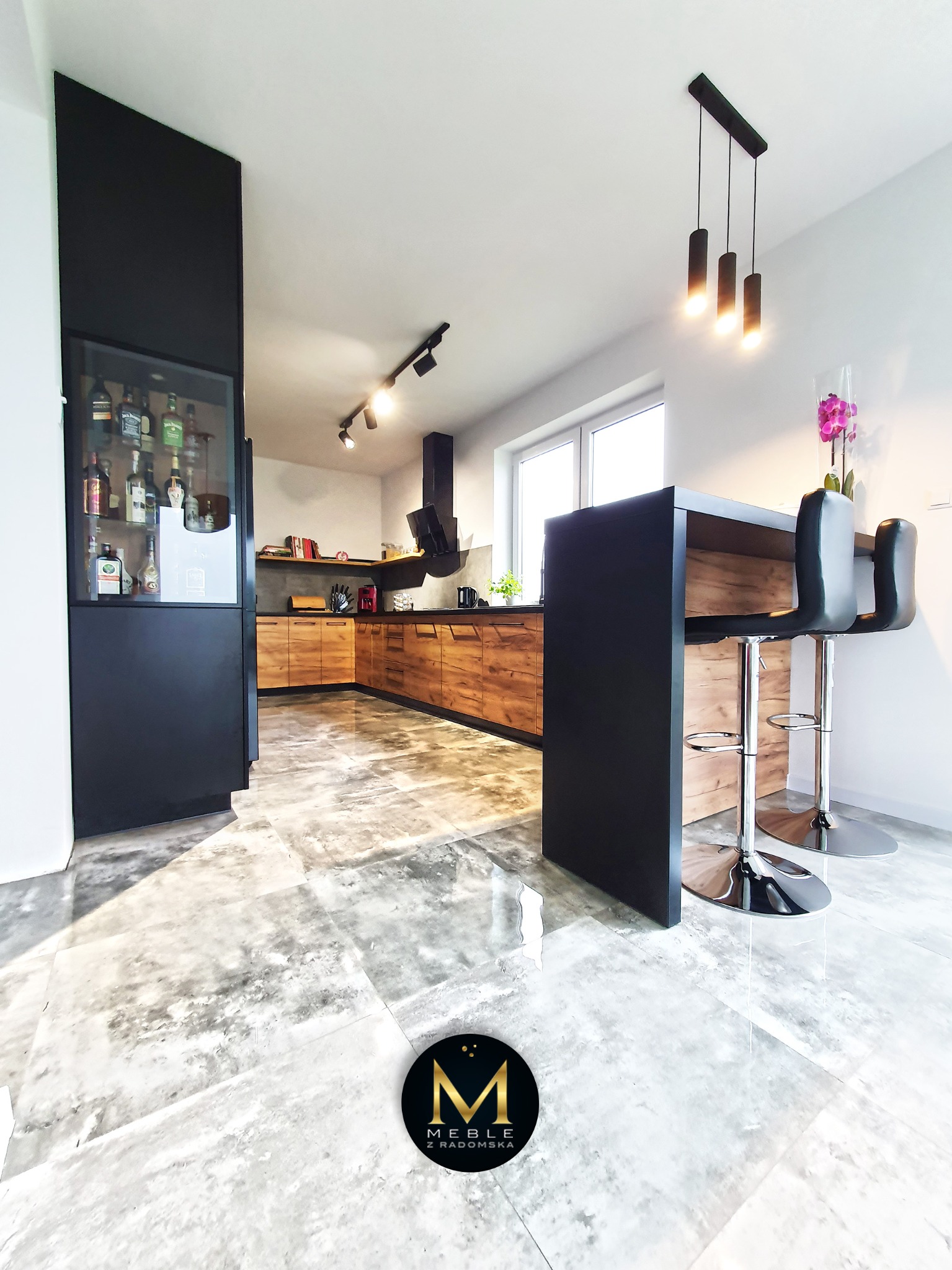 Nowoczesna kuchnia z drewnianymi frontami szafek, czarnym barkiem z hokerami i szklaną witryną na alkohol, oświetlona lampami punktowymi i wiszącymi, z marmurową podłogą.