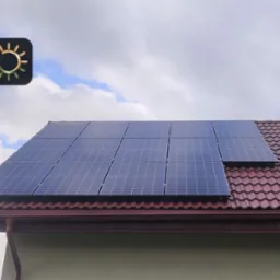 Panele słoneczne na czerwonym dachu domu jednorodzinnego, widok z dołu, częściowo zachmurzone niebo w tle, w lewym górnym rogu grafika informacyjna z nazwą Okonek i mocą 5,75 kWp.