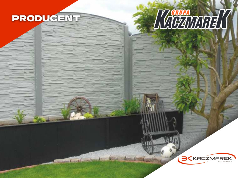 Szary panel imitujący kamień, tworzący element ogrodzenia, z dekoracyjną rabatą kwiatową i elementami ozdobnymi, takimi jak metalowe koło od wozu i krzesło bujane, całość uzupełniona drzewem i logo...