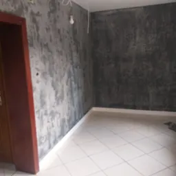 Wnętrze pokoju po nałożeniu dekoracyjnej, ciemnoszarej gładzi imitującej beton, widoczne niedokończone podłączenie oświetlenia.