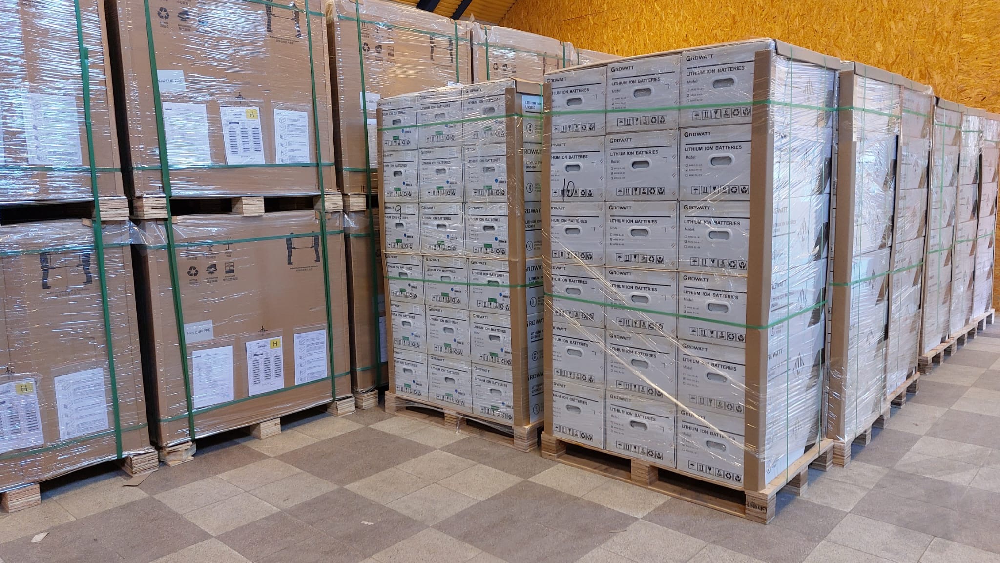 Palety z zapakowanymi kartonami akumulatorów litowo-jonowych Growatt, składowane w magazynie.