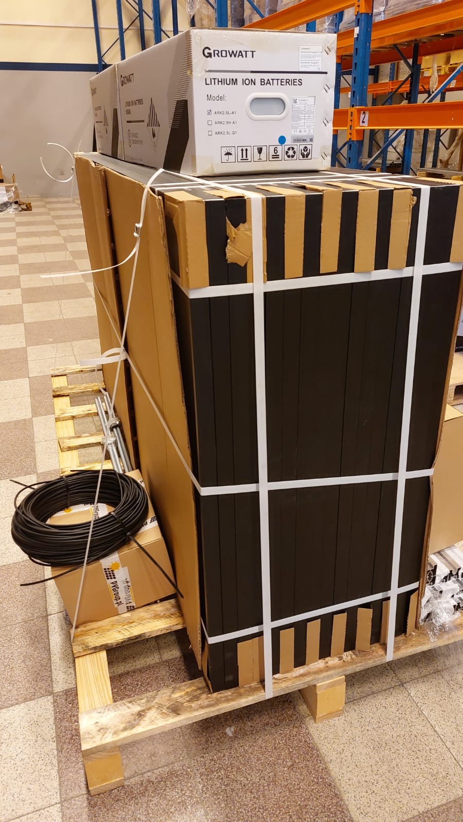 Paleta z zapakowanymi modułami akumulatorów litowo-jonowych Growatt ARK, z widocznymi kablami i elementami montażowymi, przygotowana do instalacji.