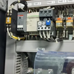 Wnętrze szafy sterowniczej z widocznymi elementami automatyki, przewodami oznaczonymi numerami i listwami zaciskowymi.