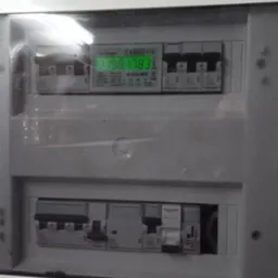 Rozdzielnica elektryczna z widocznym licznikiem zużycia energii i zabezpieczeniami nadprądowymi Legrand i Schneider, umieszczona w obudowie wnękowej.