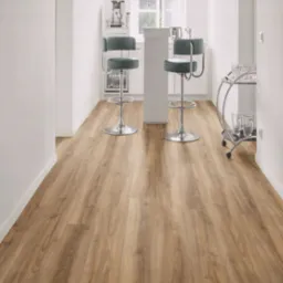 Jasnobrązowe panele podłogowe imitujące drewno, ułożone wzdłużnie w nowoczesnej, białej kuchni z barkiem, wysokimi krzesłami i przeszklonym w&oacute;zkiem na napoje.