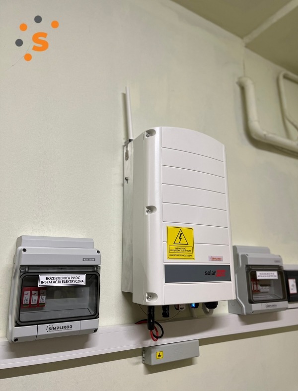 Zamontowany inwerter fotowoltaiczny SolarEdge z rozdzielnicą PV DC Simplikor w Boguchwale, widoczne kable i oznaczenia ostrzegawcze.