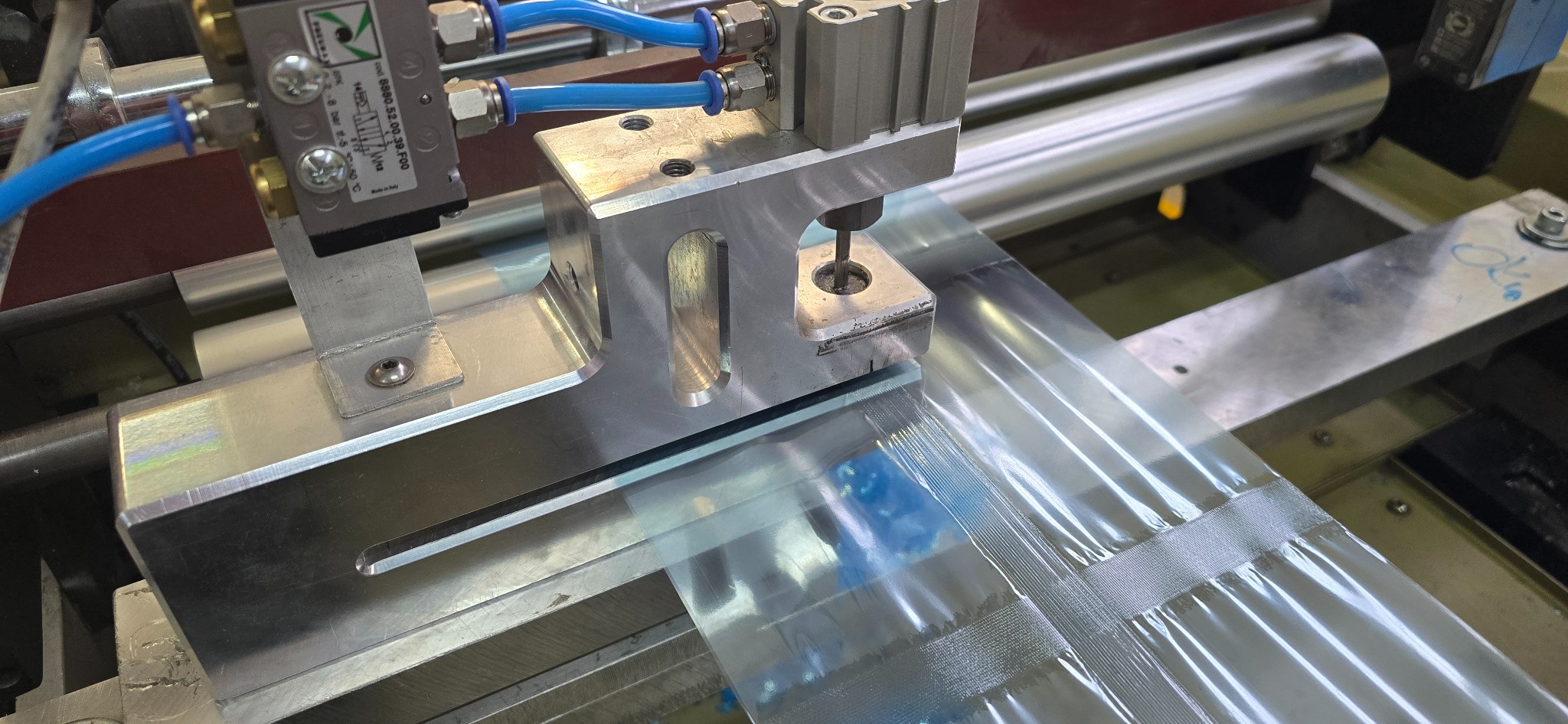 Automatyczna linia produkcyjna formująca foliowe torby zgrzewane na gorąco, z widocznym mechanizmem zgrzewającym i rolką folii.