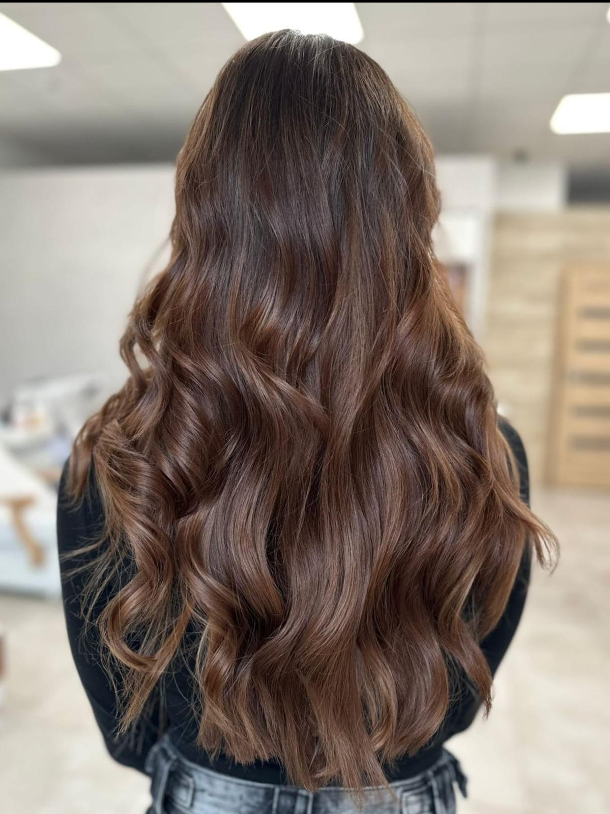 Długie, brązowe, falowane włosy, sfotografowane od tyłu w salonie w Gdańsku, z delikatnymi refleksami i subtelnym upięciem.
