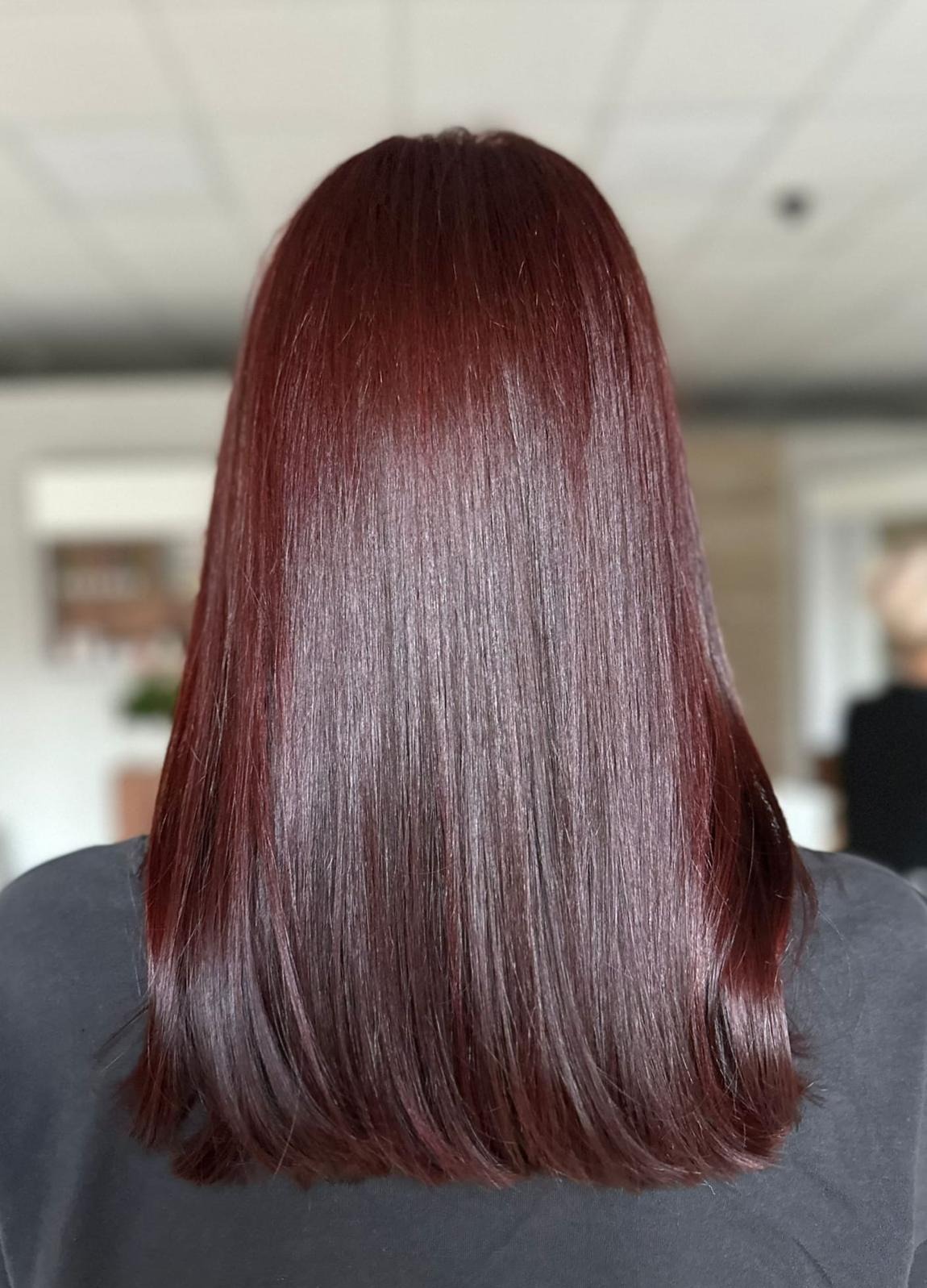 Tył głowy z długimi, prostymi włosami w odcieniu mahoniu, świeżo po koloryzacji, z delikatnym połyskiem i widoczną strukturą włosa.