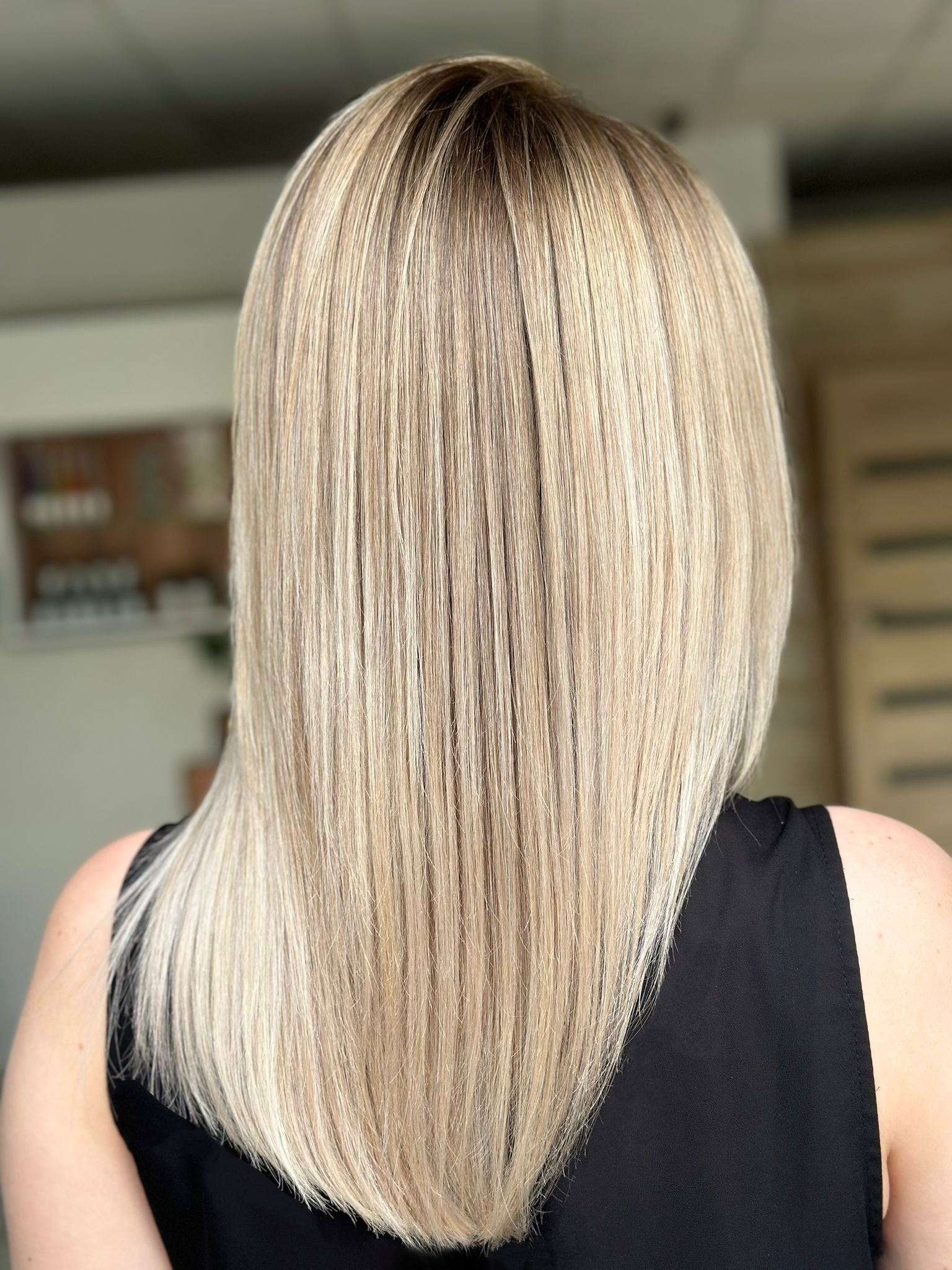 Blond włosy do ramion z ciemniejszym odrostem, widok z tyłu, gładko ułożone.