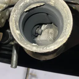 Wnętrze brudnego, metalowego układu wydechowego z widocznym wkładem katalitycznym, sfotografowane w Słubicach.