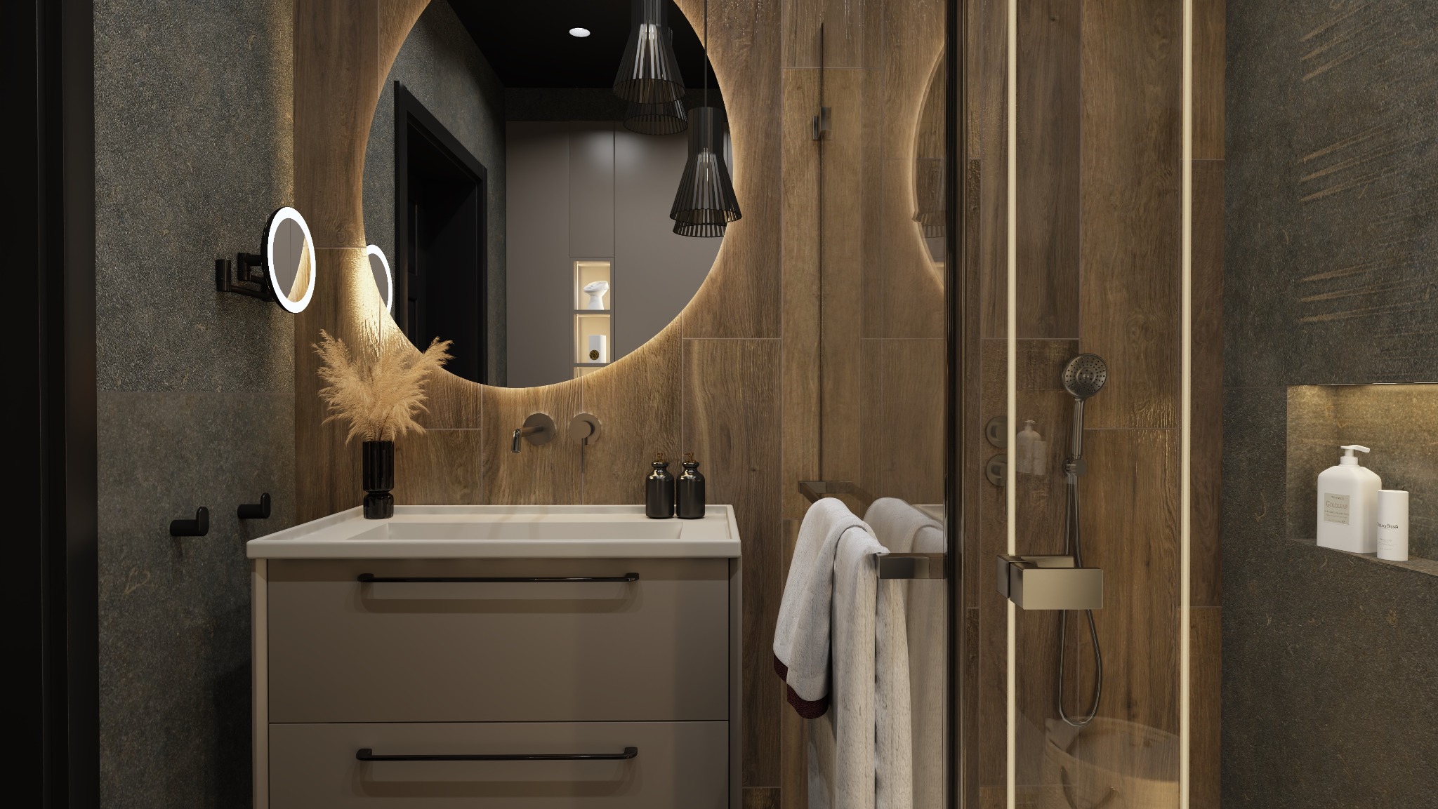 Nowoczesna łazienka z okrągłym lustrem podświetlanym LED, drewnopodobnymi płytkami, szarą szafką pod umywalką i czarnymi akcentami, takimi jak armatura i dekoracyjny wazon z suszonymi trawami.