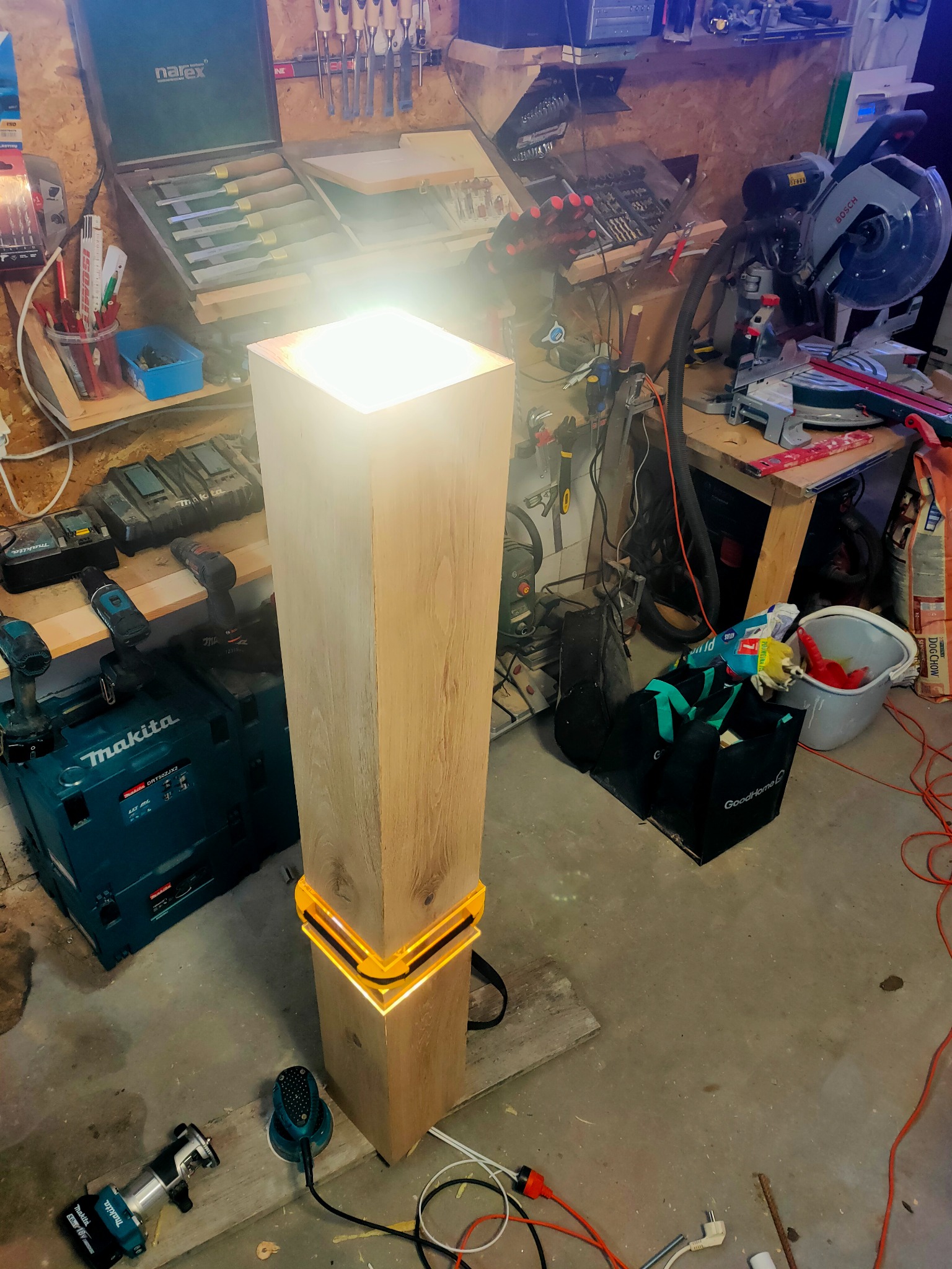 Prostopadłościenna lampa z drewna z podświetleniem LED w warsztacie, narzędzia i elektronarzędzia w tle.