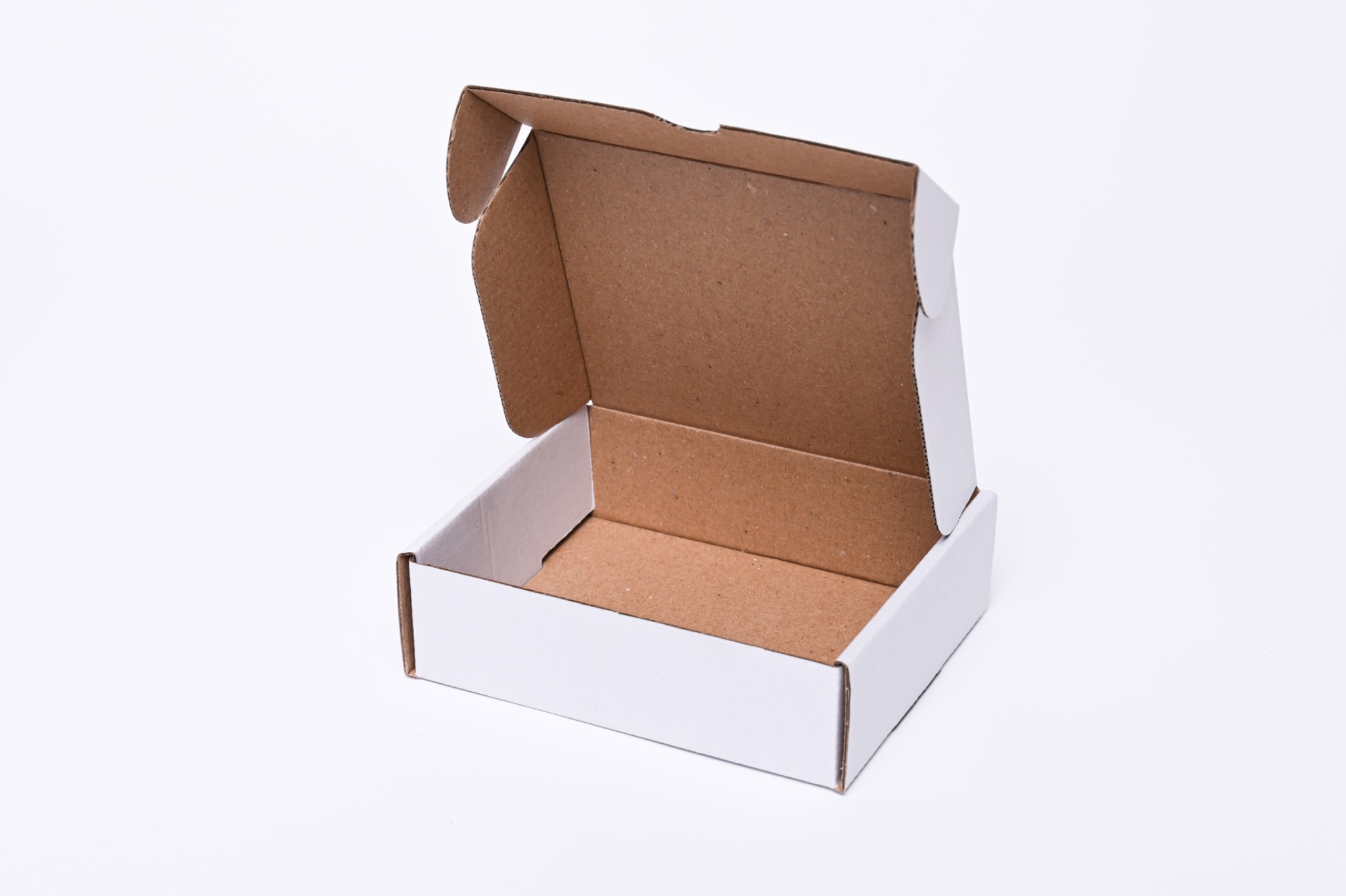 Otwarta, pusta, biała tekturowa skrzynka z brązowym wnętrzem, widoczna na białym tle, gotowa do zapakowania produktu.