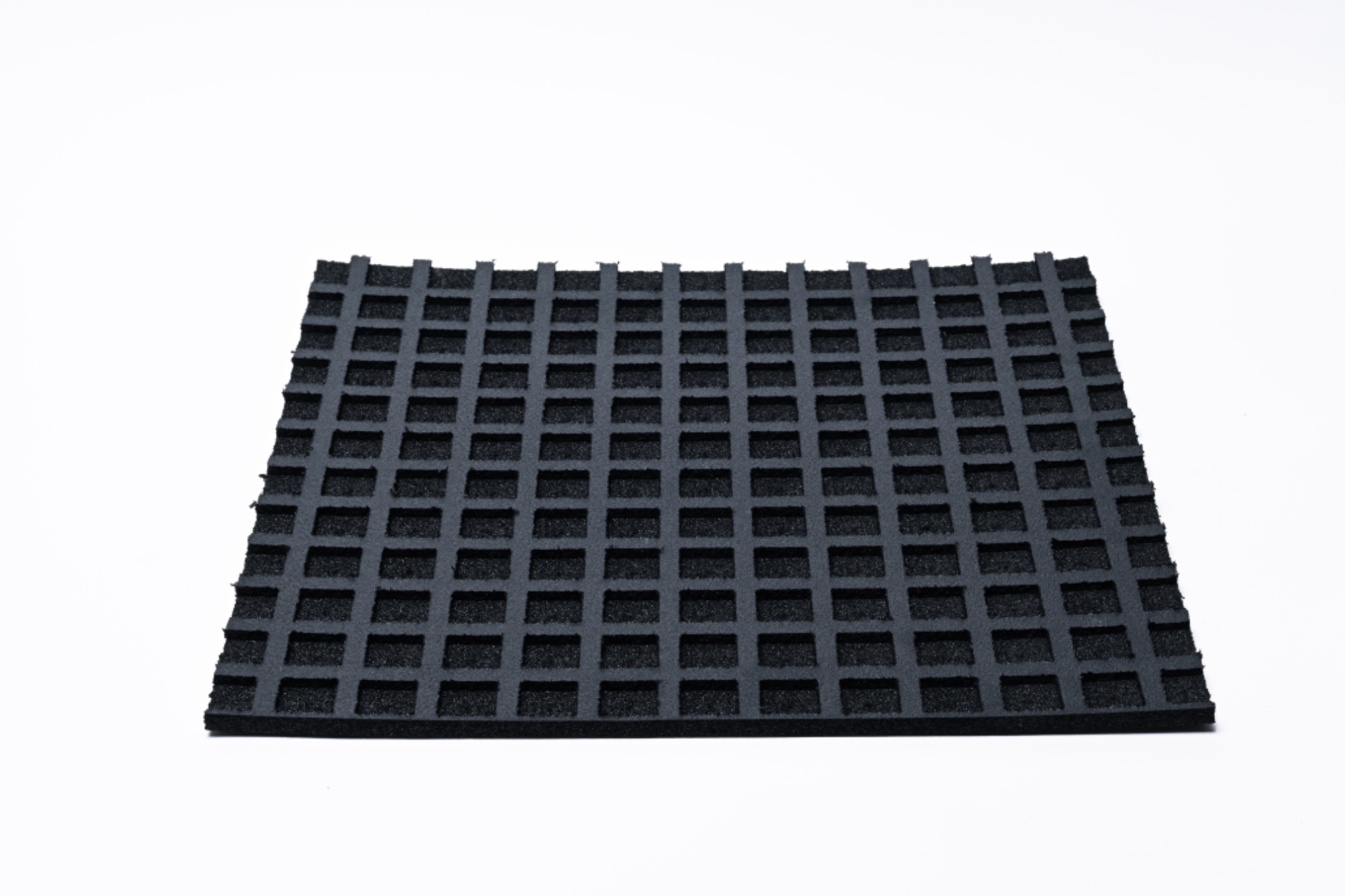 Czarna, kwadratowa podkładka z pianki o strukturze kratownicy na białym tle, potencjalnie używana jako wypełnienie ochronne lub element amortyzujący wewnątrz opakowania.